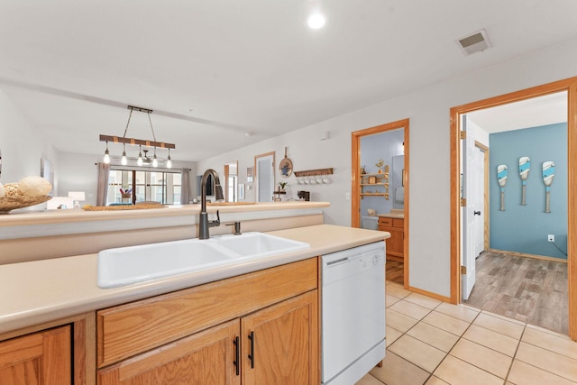 kitchen featuring dishwasher, a sink, light countertops, light tile patterned flooring, and open floor plan