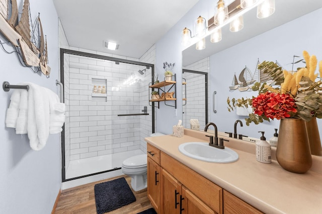 bathroom featuring wood finished floors, a stall shower, toilet, and vanity