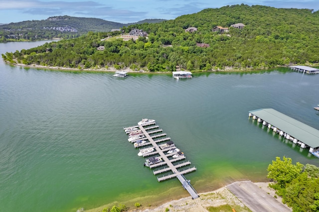 drone / aerial view of a heavily wooded area and a water and mountain view
