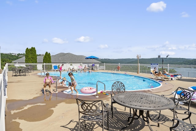 community pool featuring fence, a patio, and a mountain view