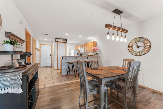 dining area with light wood-style floors, recessed lighting, and baseboards