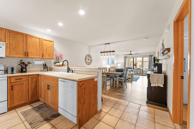 kitchen with white appliances, a peninsula, a sink, light countertops, and recessed lighting