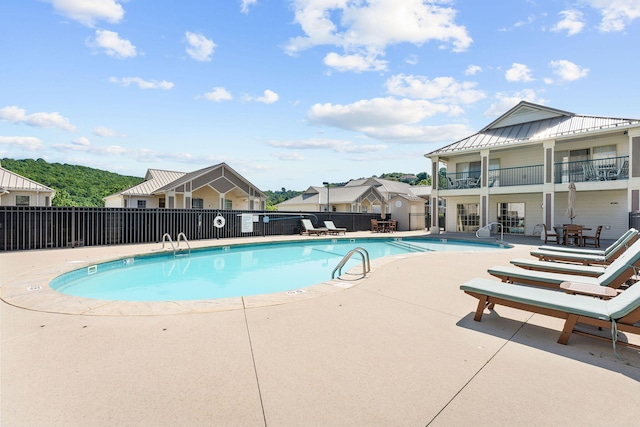 community pool with a patio, fence, and a residential view