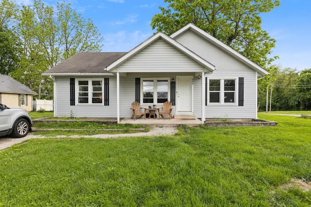 view of front of house with a front lawn, a porch, and roof with shingles