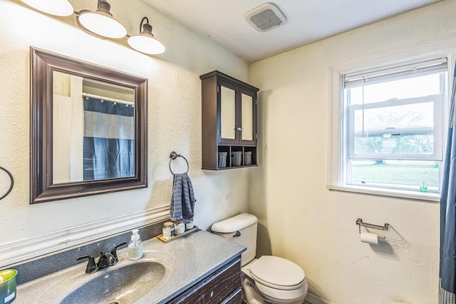 full bath featuring healthy amount of natural light, vanity, and toilet