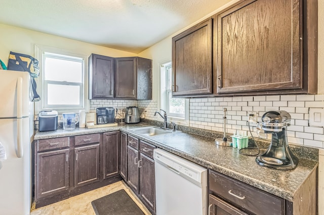 kitchen featuring white appliances, a sink, backsplash, dark brown cabinetry, and a textured ceiling