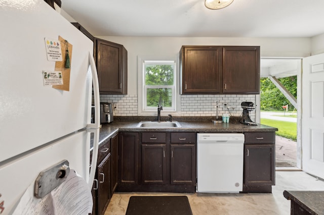 kitchen with white appliances, a sink, dark countertops, backsplash, and dark brown cabinets