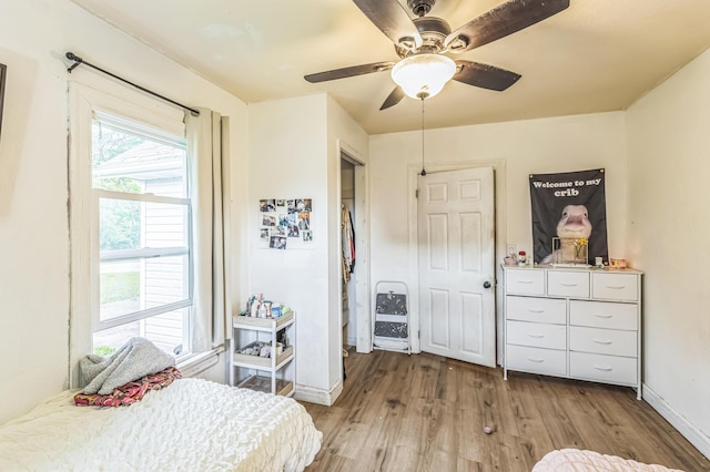 bedroom featuring wood finished floors, multiple windows, baseboards, and a ceiling fan