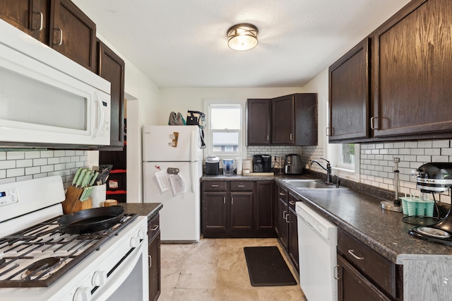 kitchen with white appliances, a sink, healthy amount of natural light, and dark brown cabinetry