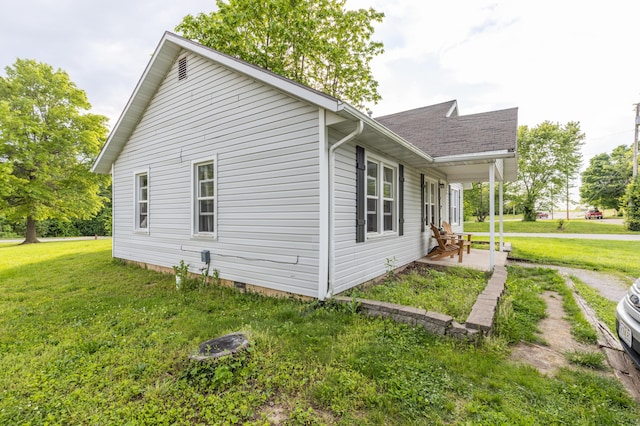 view of side of property featuring a lawn and a shingled roof