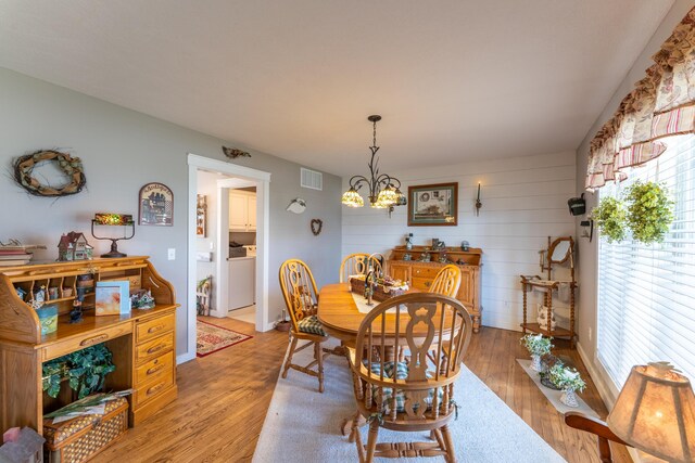 522 E Grace St, Republic, MO 65738 - dining room featuring healthy amount of natural light, light wood-type flooring, a chandelier, washer / clothes dryer, and wooden walls