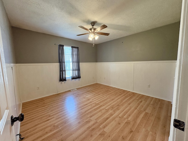 707 S Eastridge, Nixa, MO 65714 - unfurnished room featuring ceiling fan, a textured ceiling, a wainscoted wall, and light wood finished floors