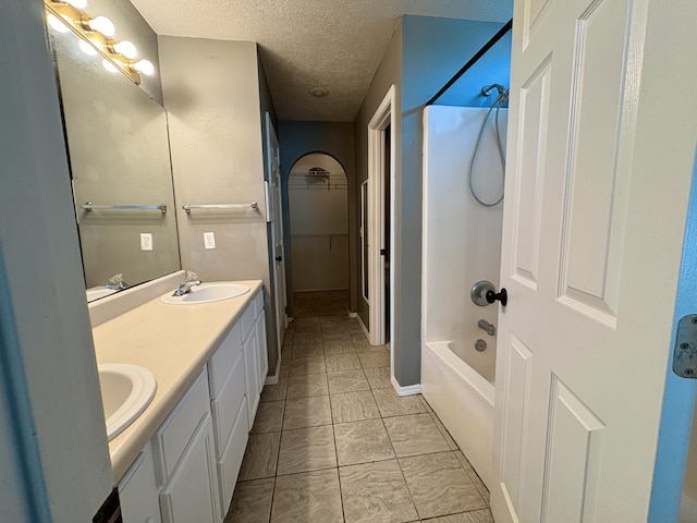 707 S Eastridge, Nixa, MO 65714 - bathroom featuring double vanity, a textured ceiling, shower / bath combination, marble look tiles, and a walk in closet