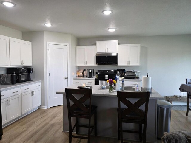 552 S Michelle Ave, Republic, MO 65738 - kitchen with black / electric stove, a kitchen breakfast bar, white cabinets, light wood finished floors, and recessed lighting