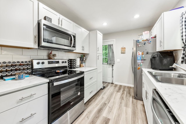 2221 W Nichols St, Springfield, MO 65802 - kitchen featuring appliances with stainless steel finishes, white cabinetry, backsplash, a sink, and light wood-type flooring