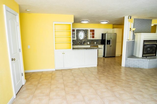 358 High Ridge Rd, Marshfield, MO 65706 - kitchen featuring stainless steel fridge, a peninsula, white cabinetry, light tile patterned floors, and a fireplace