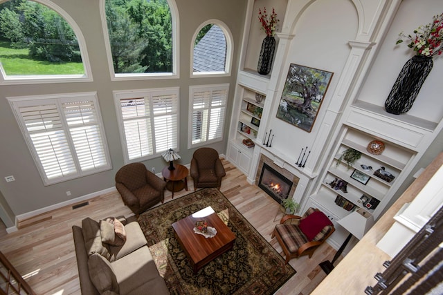 5853 S Northern Ridge Rd, Springfield, MO 65810 - living area featuring a tiled fireplace, light wood finished floors, ornate columns, a high ceiling, and baseboards