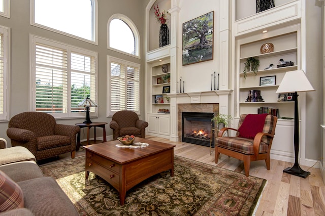 5853 S Northern Ridge Rd, Springfield, MO 65810 - living area featuring built in shelves, a tiled fireplace, light wood finished floors, a high ceiling, and baseboards