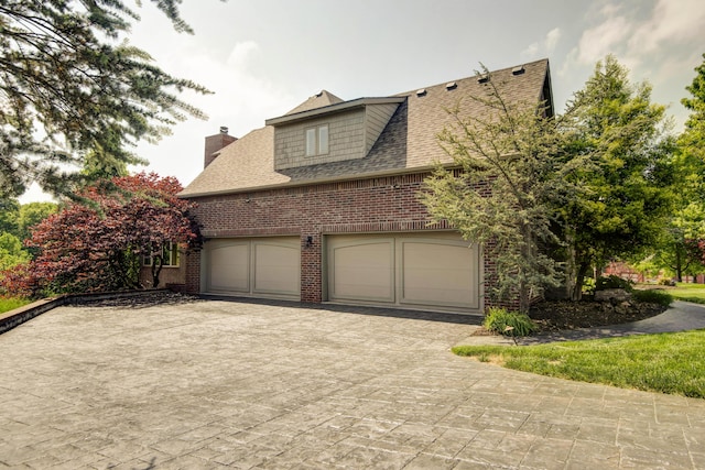 5853 S Northern Ridge Rd, Springfield, MO 65810 - view of property exterior with brick siding, roof with shingles, a chimney, driveway, and an attached garage