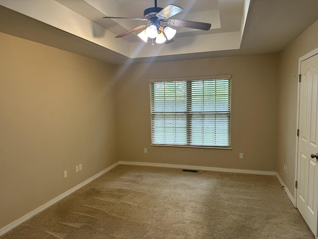 unfurnished bedroom with a raised ceiling, carpet flooring, baseboards, and a ceiling fan