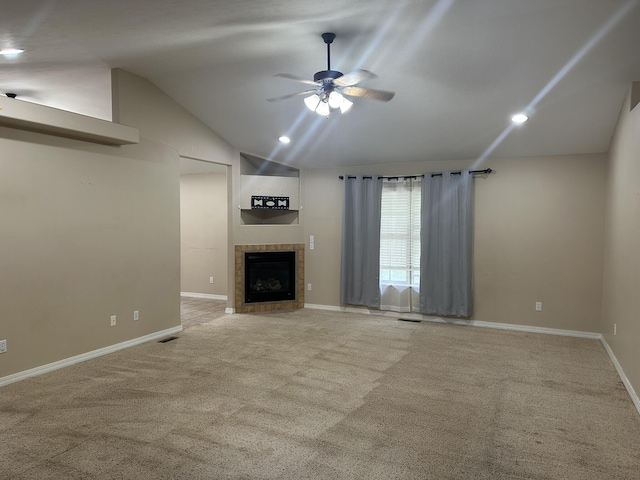 unfurnished living room featuring ceiling fan, vaulted ceiling, carpet flooring, a tile fireplace, and baseboards