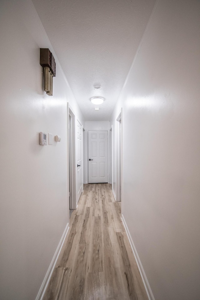 hallway featuring light wood-type flooring and baseboards