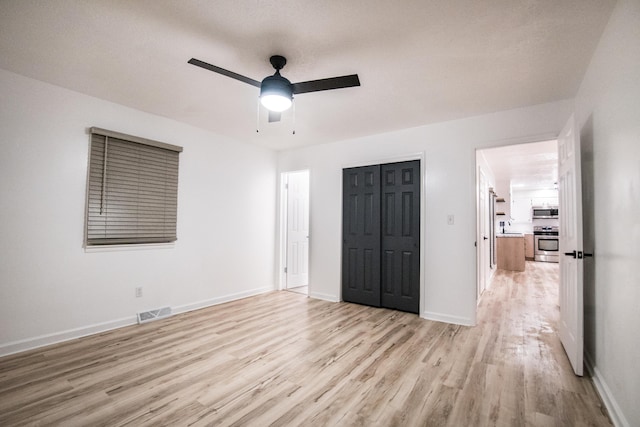 unfurnished bedroom with light wood-type flooring, a sink, baseboards, a closet, and ceiling fan