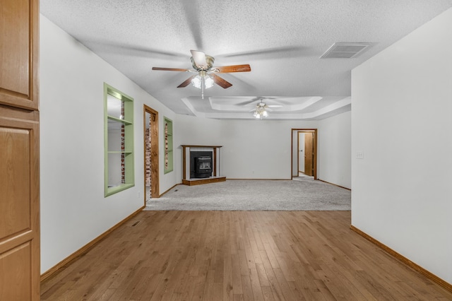 3563 S Western Ave, Springfield, MO 65807 - unfurnished living room featuring a ceiling fan, a textured ceiling, baseboards, light wood-style floors, and a tray ceiling