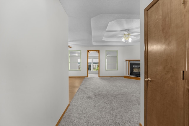 3563 S Western Ave, Springfield, MO 65807 - unfurnished living room with a ceiling fan, baseboards, a raised ceiling, a fireplace with raised hearth, and a textured ceiling