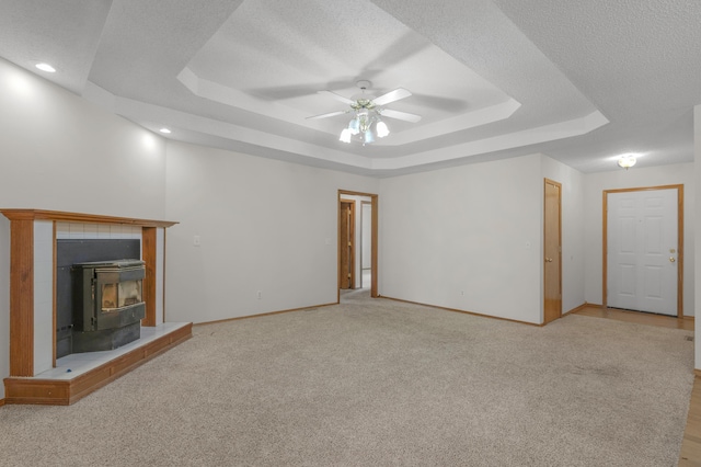 3563 S Western Ave, Springfield, MO 65807 - unfurnished living room with a raised ceiling, ceiling fan, a wood stove, light colored carpet, and baseboards