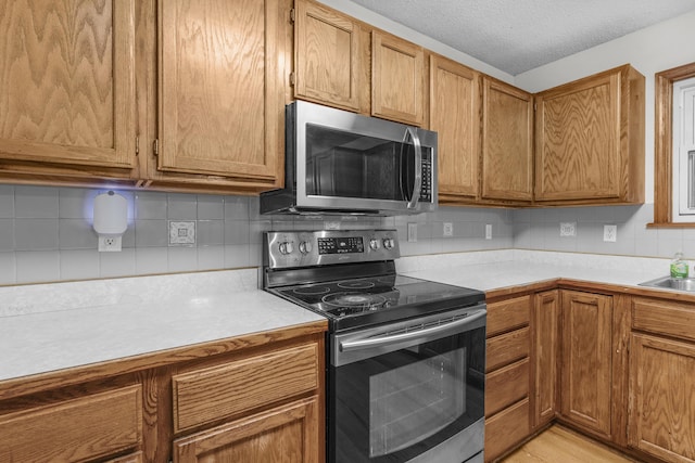 3563 S Western Ave, Springfield, MO 65807 - kitchen featuring appliances with stainless steel finishes, light countertops, decorative backsplash, brown cabinetry, and a sink