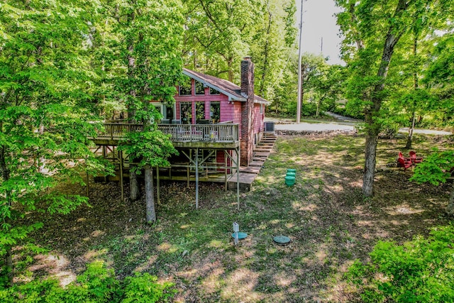 view of yard with a deck, stairs, and a forest view