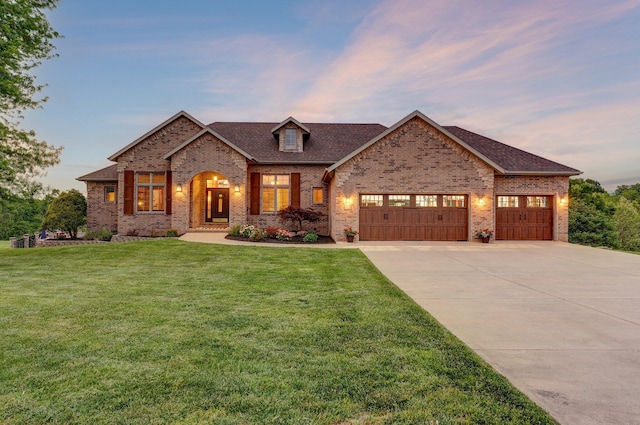 view of front facade with brick siding, a garage, driveway, a lawn, and a shingled roof