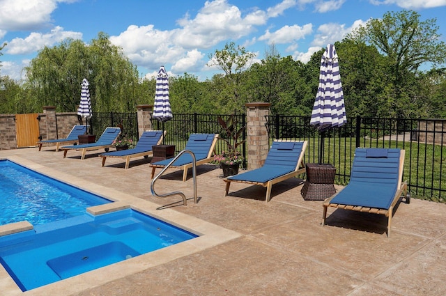 view of pool with a patio area, fence, and a pool with connected hot tub