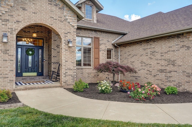 entrance to property featuring brick siding and roof with shingles