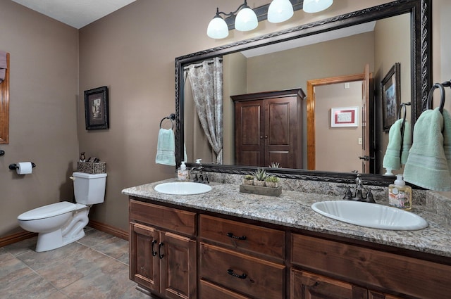 full bath featuring baseboards, toilet, and double vanity