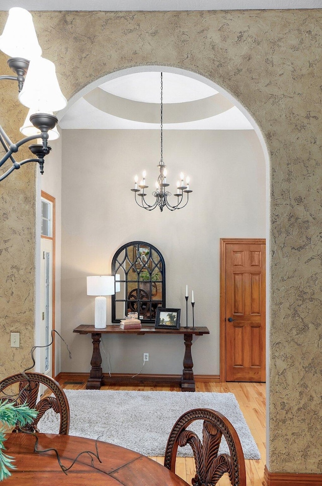 dining room with arched walkways, a chandelier, wood finished floors, and baseboards