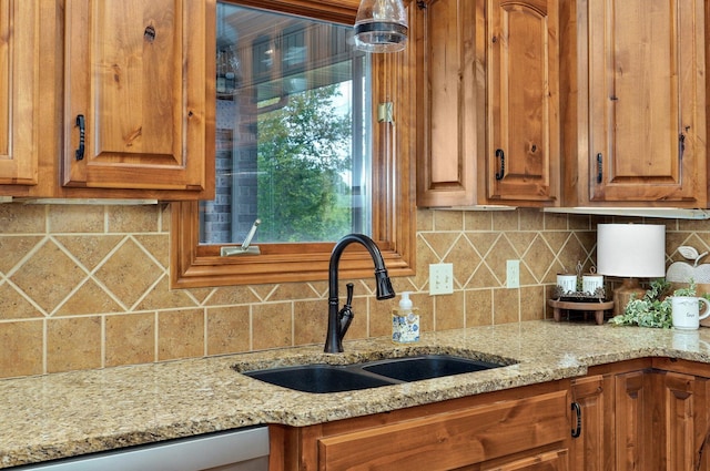 kitchen featuring a sink, backsplash, stainless steel dishwasher, and light stone counters