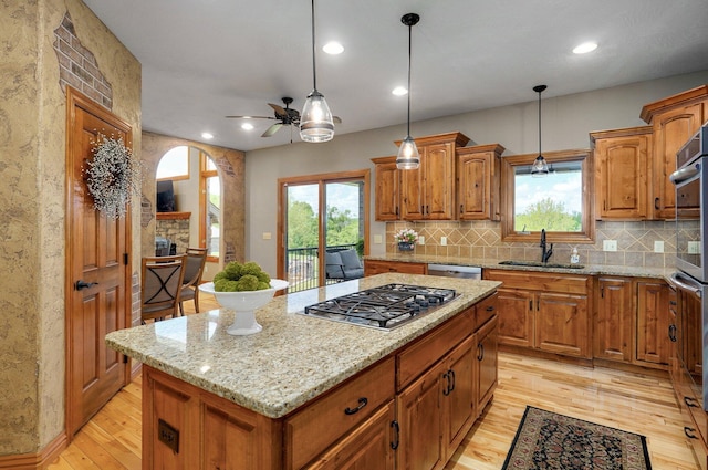 kitchen featuring appliances with stainless steel finishes, a sink, light wood-style floors, arched walkways, and ceiling fan