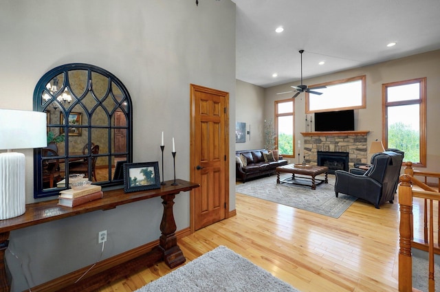 living room with a stone fireplace, ceiling fan, wood finished floors, baseboards, and recessed lighting