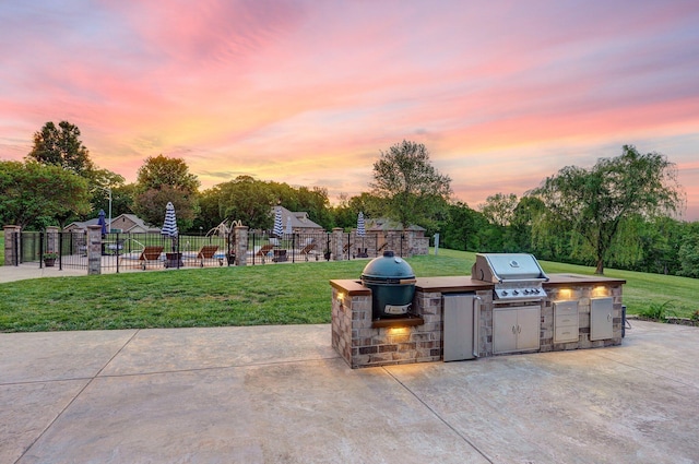 view of patio / terrace with an outdoor kitchen, a grill, and view of scattered trees