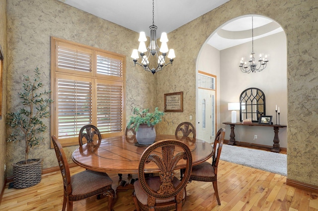 dining area with a chandelier, hardwood / wood-style flooring, arched walkways, and plenty of natural light