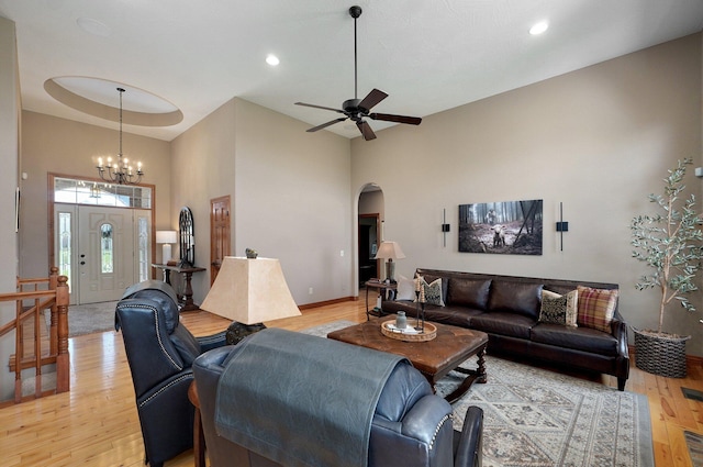 living room featuring a high ceiling, arched walkways, light wood finished floors, ceiling fan, and recessed lighting