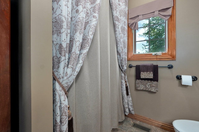 full bath with toilet, baseboards, and curtained shower