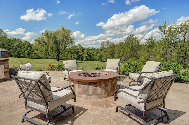 view of patio featuring a fire pit and a wooded view