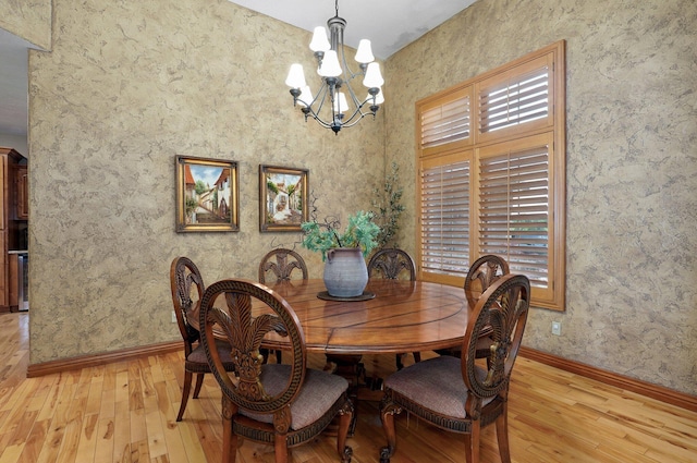 dining room featuring light wood-type flooring, a chandelier, and baseboards