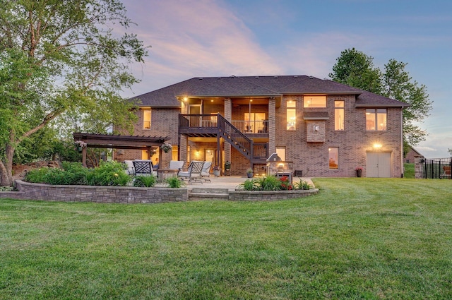 back of property at dusk featuring brick siding, a patio, and a yard