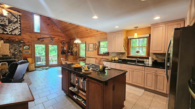 kitchen with open floor plan, a sink, freestanding refrigerator, wooden walls, and ceiling fan