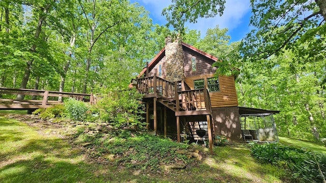 back of house with a wooden deck, log veneer siding, a chimney, and stairway