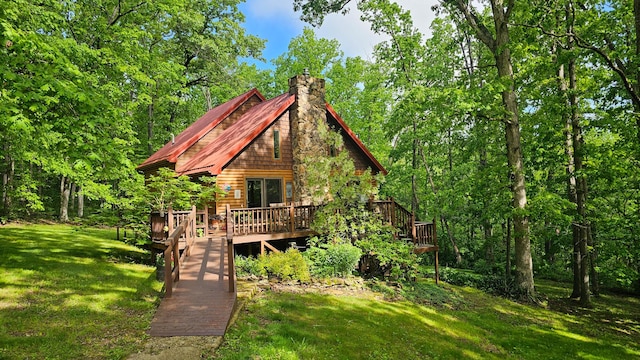 view of front facade featuring a deck, a front yard, a chimney, and metal roof